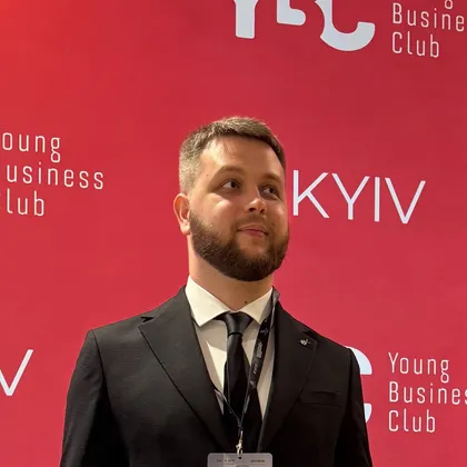 Богдан Щербаков у чорному костюмі на червоному фоні Young Business Club Kyiv